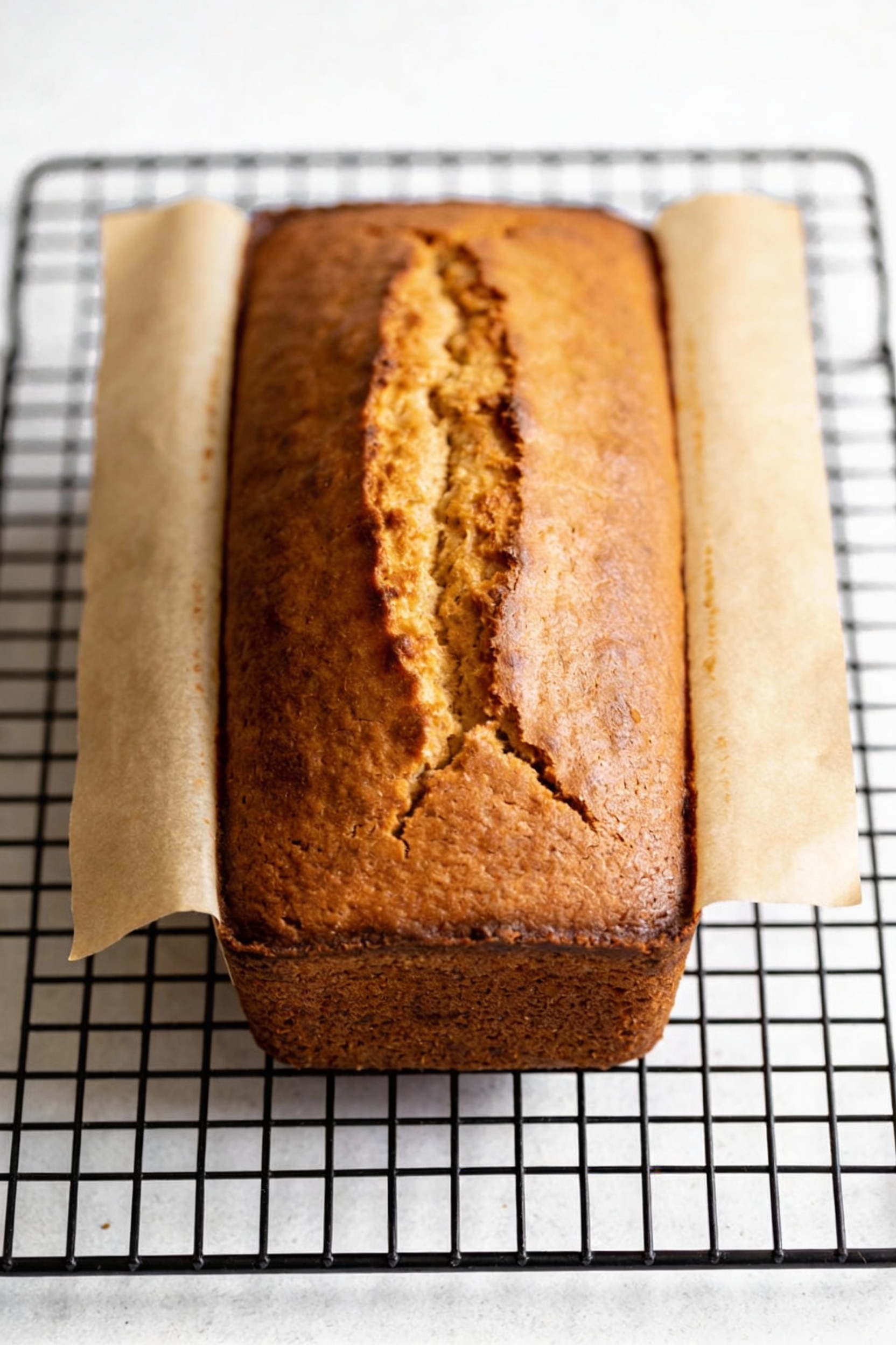 2. Pound cake cooling on a wire rack after baking, tall loaf with a classic cracked top and evenly browned golden surfac
