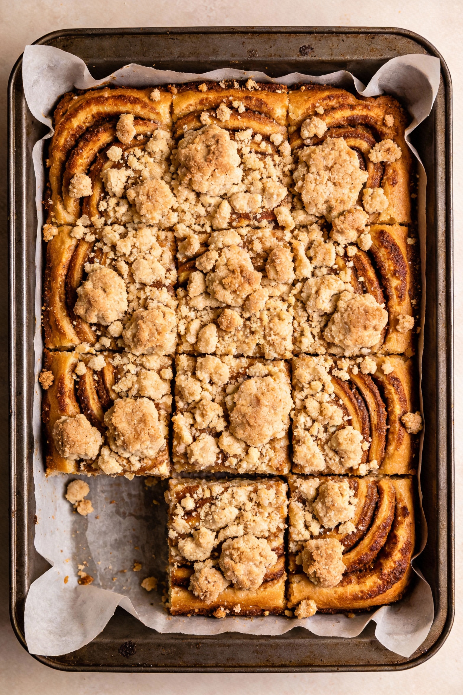2. Overhead shot of a baked 9x9-inch coffee cake in the pan lined with parchment, thick chunky streusel scattered in big