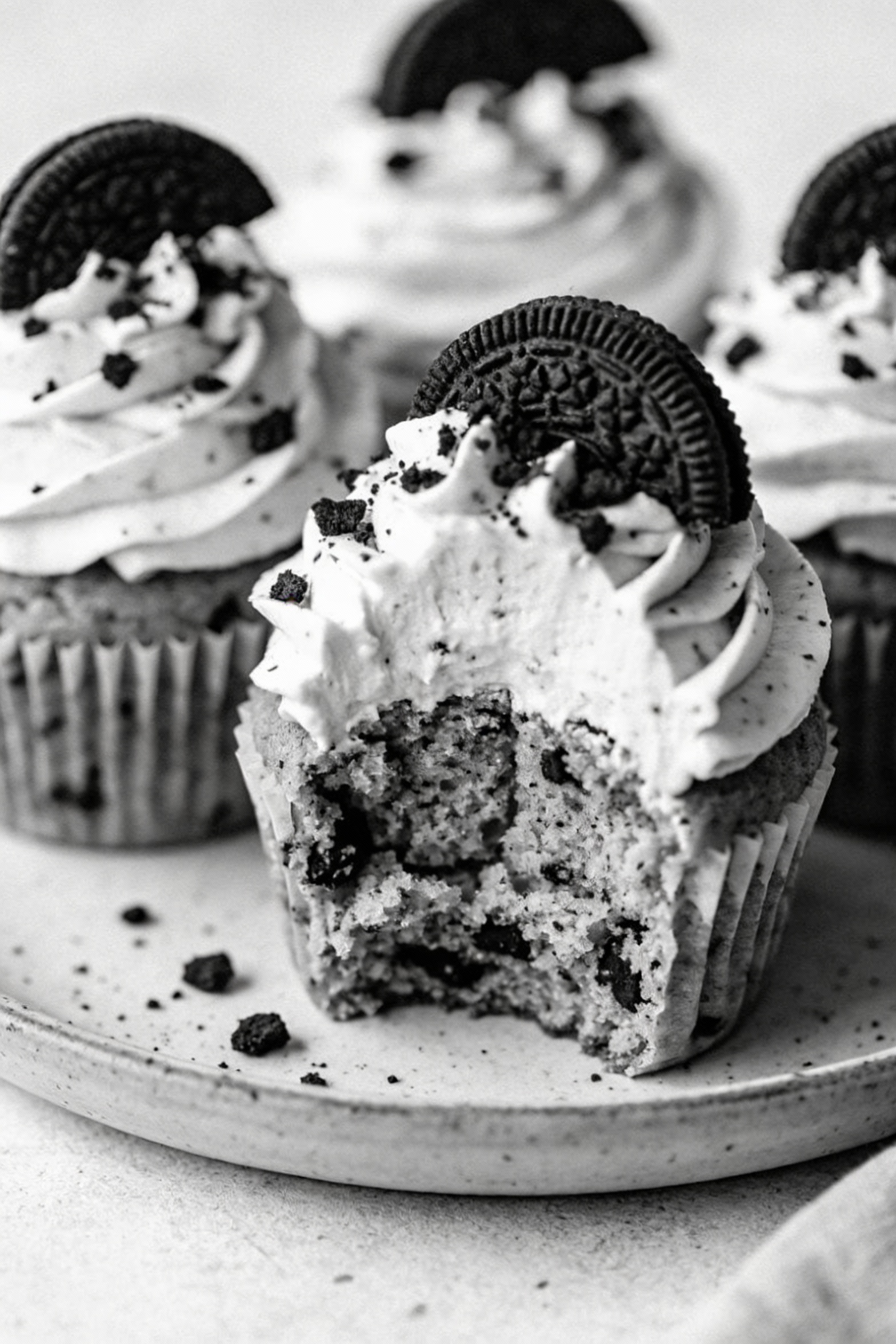 Close-up detail of cookies-and-cream cupcakes: tall vanilla frosting swirls topped with chocolate sandwich cookie crumbs