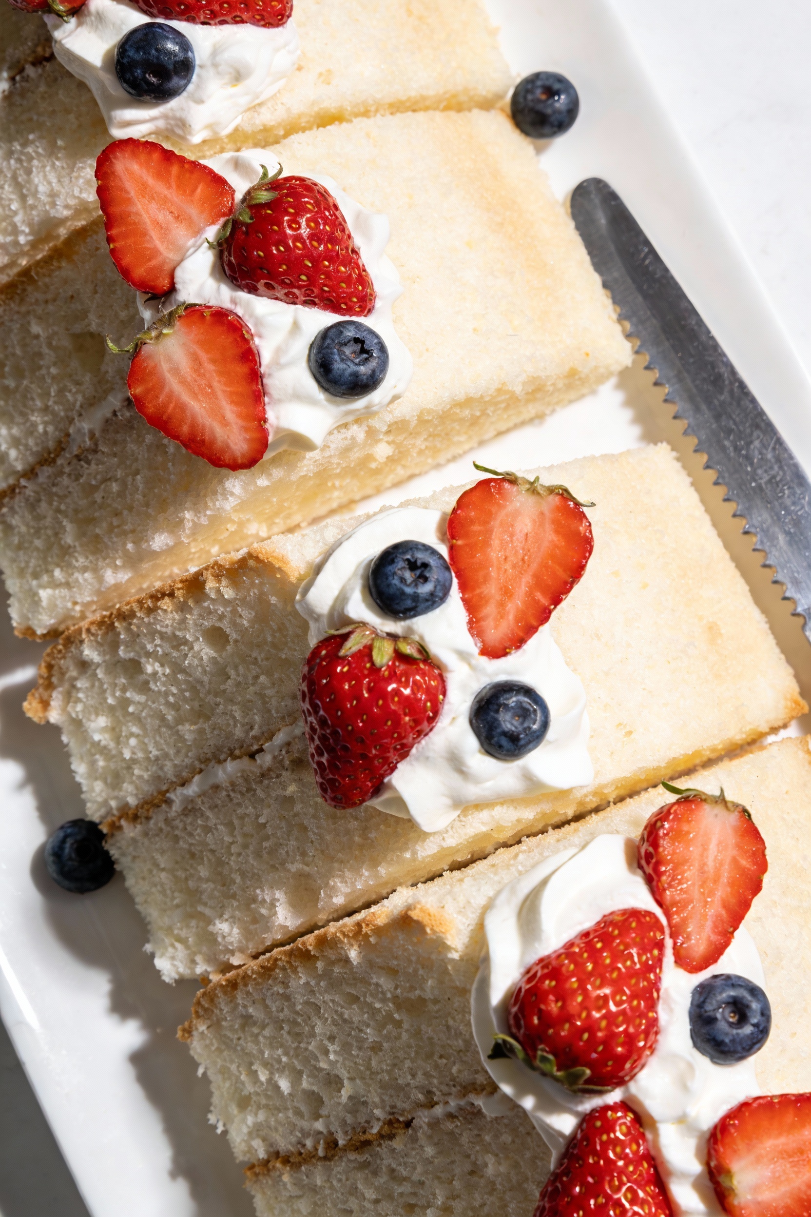 Tasty top view: overhead shot of tall angel food cake slices arranged on a white platter, cloud-light snowy crumb and cl