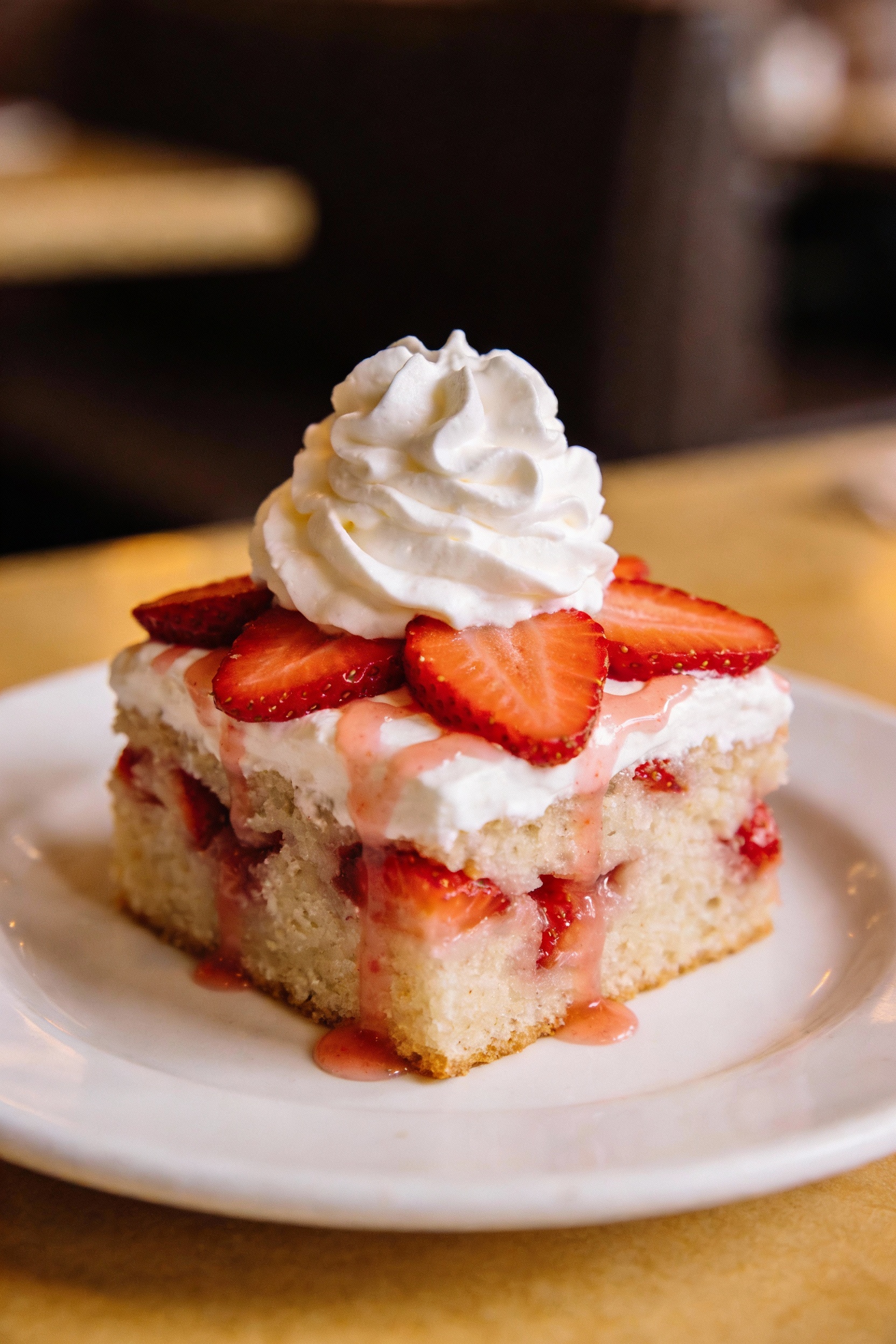 Final plated dish: a single square of strawberries-and-cream poke cake on a white dessert plate, fluffy whipped topping 