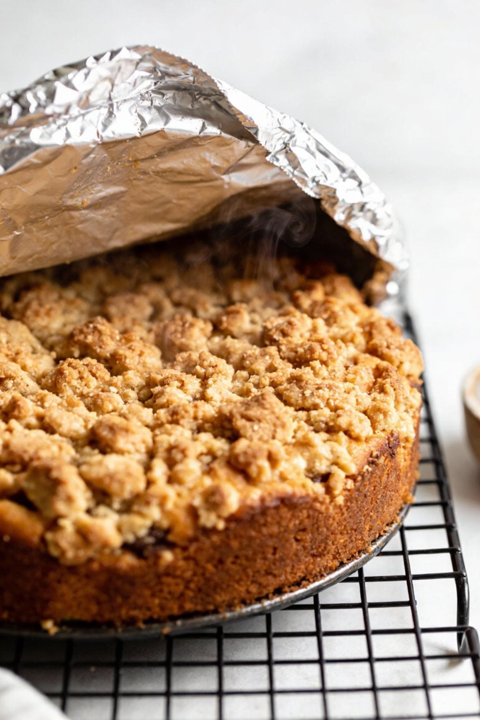 3. Cooking process: coffee cake fresh from the oven with a foil tent partially lifted back to show the deeply golden str