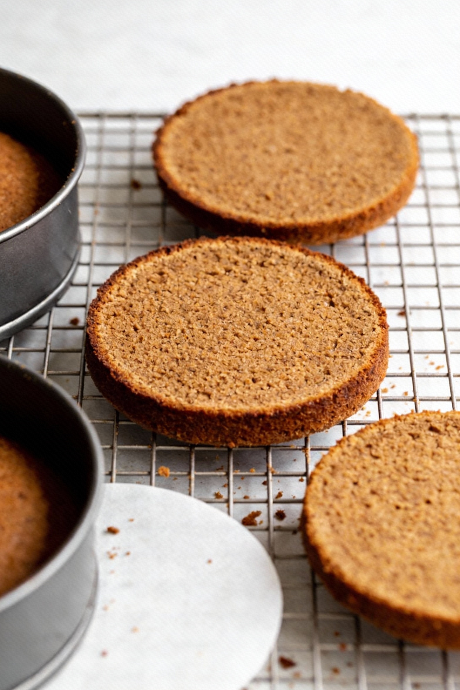 Cooking process: freshly baked spice cake layers cooling on a wire rack after being turned out of the pans, lightly brow